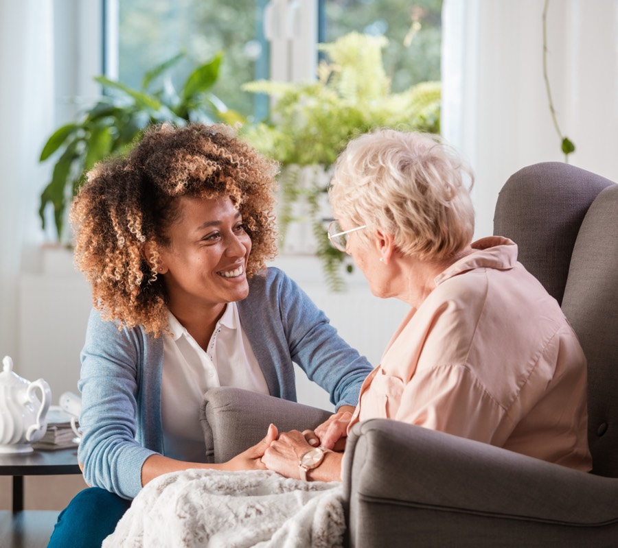 Aidant tenant la main d'une personne âgée dans un cadre familial
